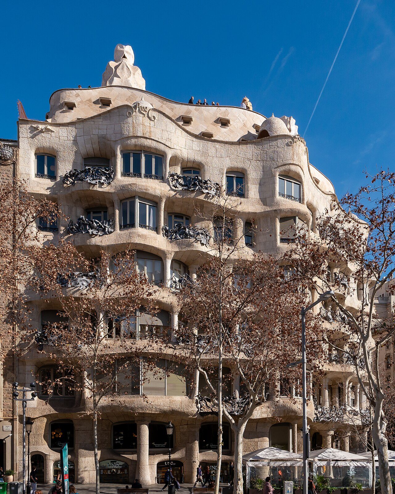 The wavy stone façade and balconies of La Pedrera on Passeig de Gràcia, under a blue sky